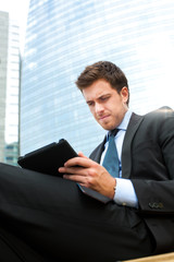 Fototapeta premium Businessman using a tablet on a bench in the city