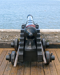 Old canon aiming at the sea, on an overcast day.