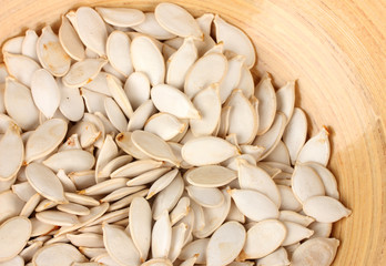 Pumpkin seeds in wooden bowl, close up