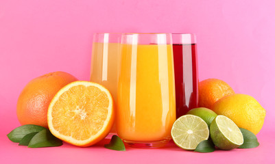 Glasses of juise with leafs and fruits on pink background