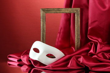 White mask, empty frame and golden silk fabric,