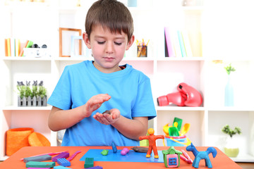 Cute little boy moulds from plasticine on table