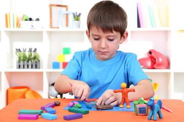Cute little boy moulds from plasticine on table