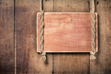 Wooden signboard blank with rope on wall background