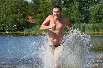 Happy strong man running on the water at beach