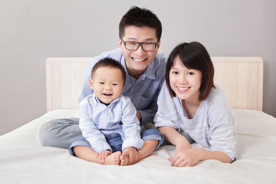 A happy family sitting on white bed