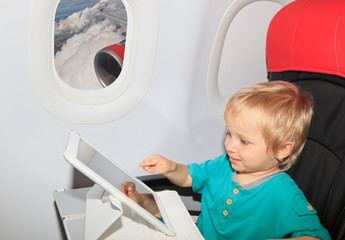 little boy with touch pad on plane in flight