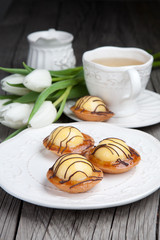 Sweet cakes with cup of tea and flowers on wooden table