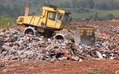 A bulldozer moving garbage on a landfill waste site