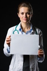 Medical doctor woman showing blank billboard isolated on black