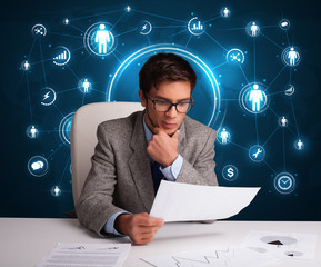 Businessman sitting at desk with social network icons