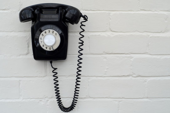 Black bakelite telephone on a brick wall
