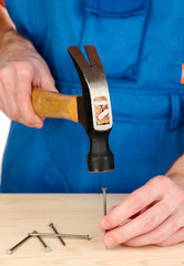 Builder hammering nails into board isolated on white