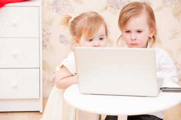 Children with laptop indoors.