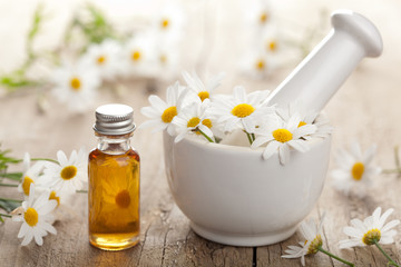 essential oil and camomile flowers in mortar - obrazy, fototapety, plakaty