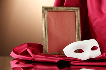 White mask, empty frame and golden silk fabric,