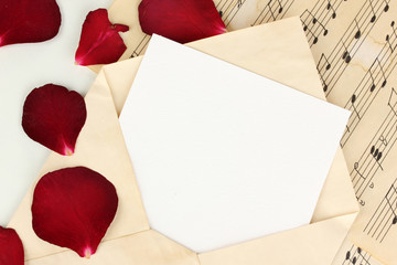 Old envelope with blank paper and dried rose petals