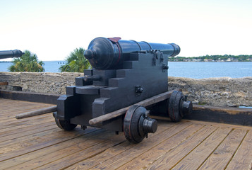 Old canon aiming at the sea, on an overcast day.