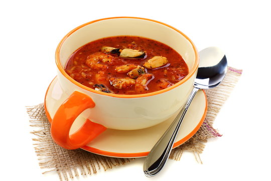 Cup of soup with seafood and tomato.