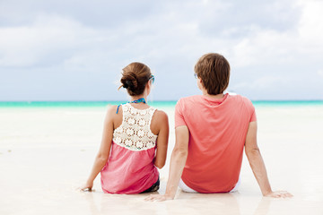 beautiful young couple sitting and having fun on beach