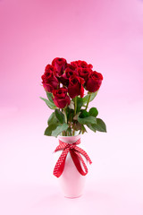 Red roses in white vase with ribbon