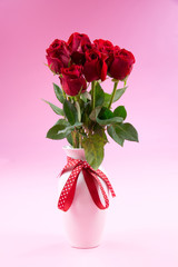 Red roses in white vase with ribbon