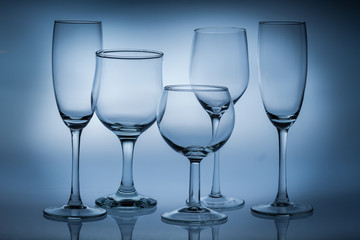 Different types of empty glasses on a blue background