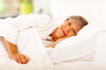 happy senior woman sleeping on bed