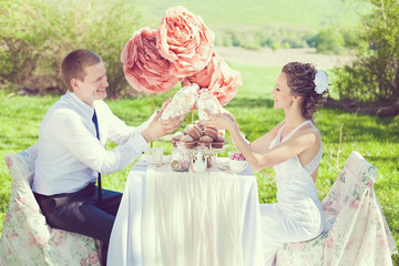 Bride and groom posing at the decorated banquet table in park