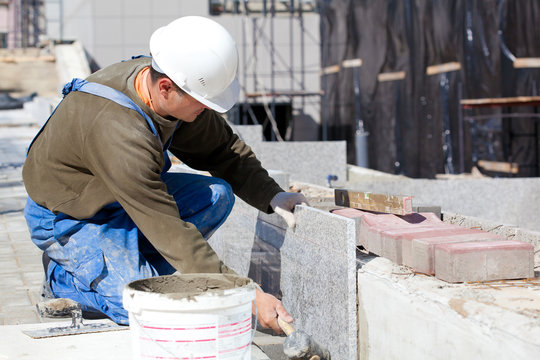 Tiler in helmet and work wear installing marble tiles