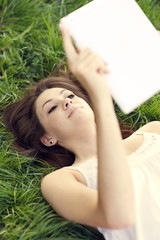 Obraz na płótnie Canvas Young woman using digital tablet on meadow