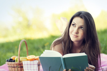 Fototapeta premium Young woman reading on meadow