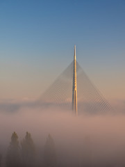 Cable bridge on sunshine above a fog