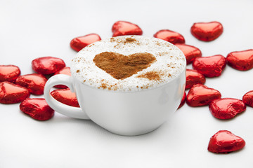 Cup of coffee with heart symbol and candy around.