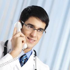 Young doctor on phone, at office