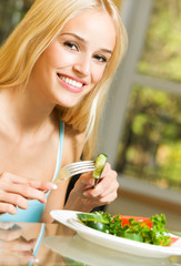 Happy smiling young woman eating salad