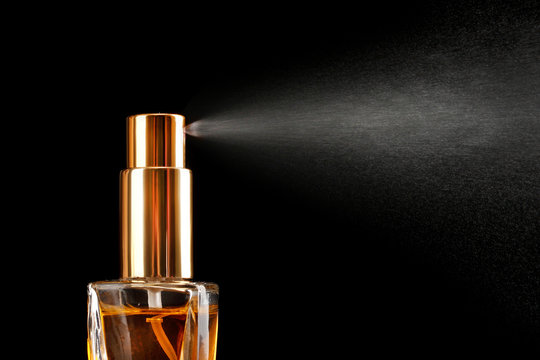 women's perfume in bottle and spraying, on black background