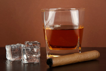 Glass of whiskey and cigar on brown background