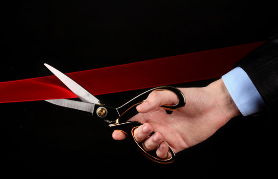 Cutting red ribbon, isolated on black