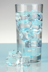 Ice cubes in glass on light blue background