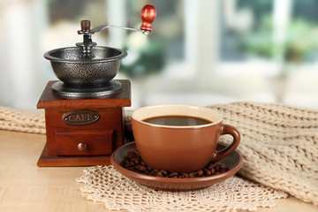 cup of coffee with scarf and coffee mill on table in room