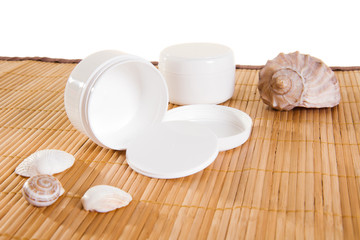 Fototapeta na wymiar Empty cream jars on bamboo mat