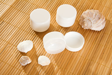 Fototapeta na wymiar Empty cream jars on bamboo mat