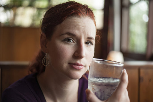 Young Woman with Beautiful Auburn Hair Drinking Water