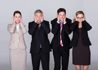 Four businesspeople holding their ears