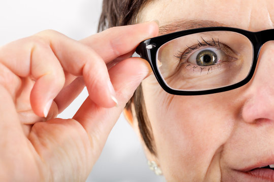 Woman holding glasses to see better