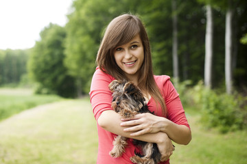Naklejka na ściany i meble Smiling woman holding cute puppy