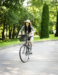 Happy young woman riding a bicycle in the park