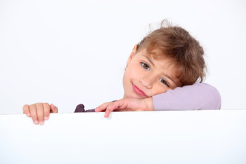Lovely little girl leaning on a white panel