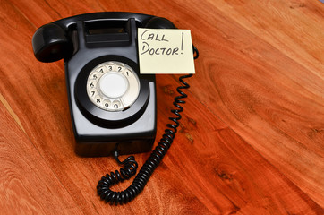 Black retro telephone with reminder note to call the doctor